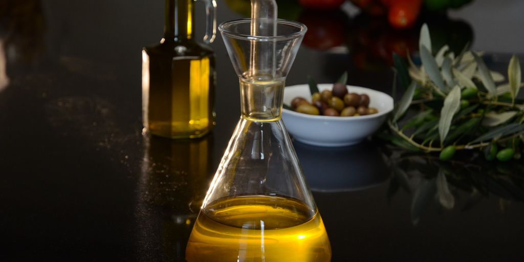 olive oil bottle with fresh olives and olive tree in background